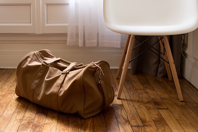 Veľká hnedá taška položená na drevenej podlahe pri stoličke